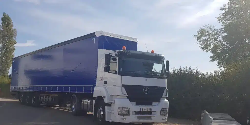 Camion Mercedes Actros 1840: Transport et semi-remorque. Camion Mercedes-Benz Actros 1840 blanc et semi-remorque bâche bleue, garés en extérieur par temps ensoleillé. Plaque W-012-JH.