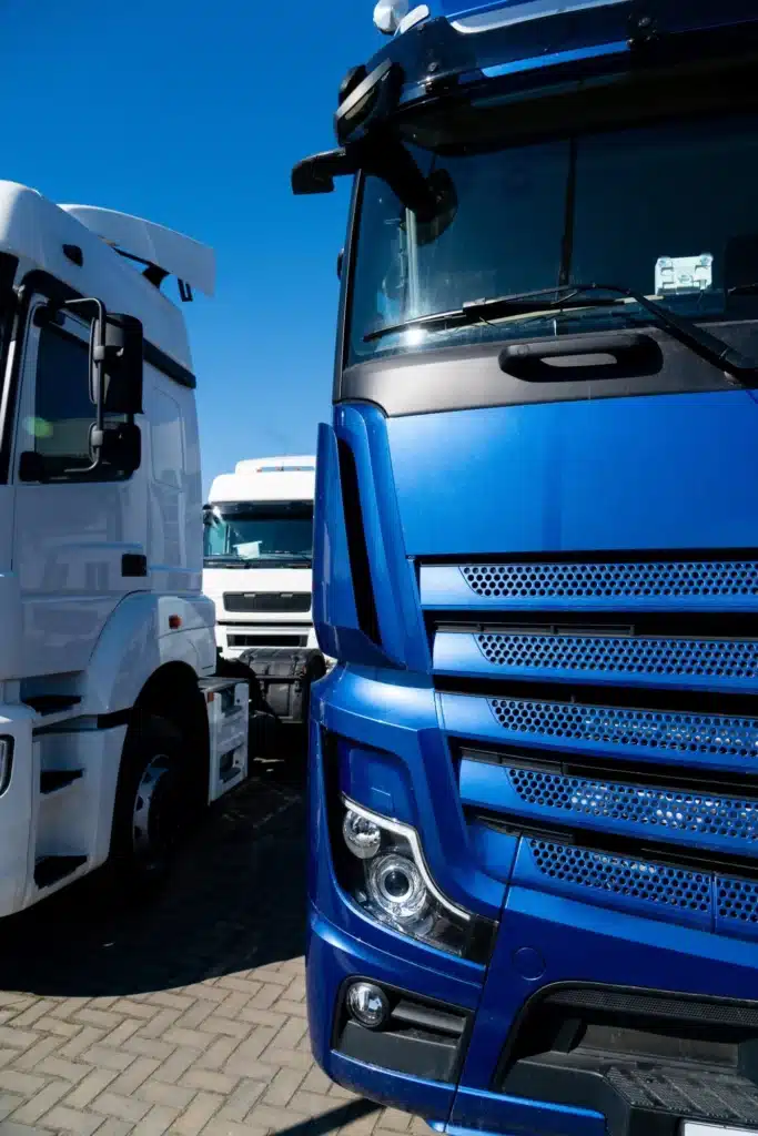 Camions Poids Lourds : Gros Plan d'un Camion Bleu Gros plan de l'avant d'un camion bleu moderne stationné à côté d'un camion blanc sous un ciel bleu dégagé.