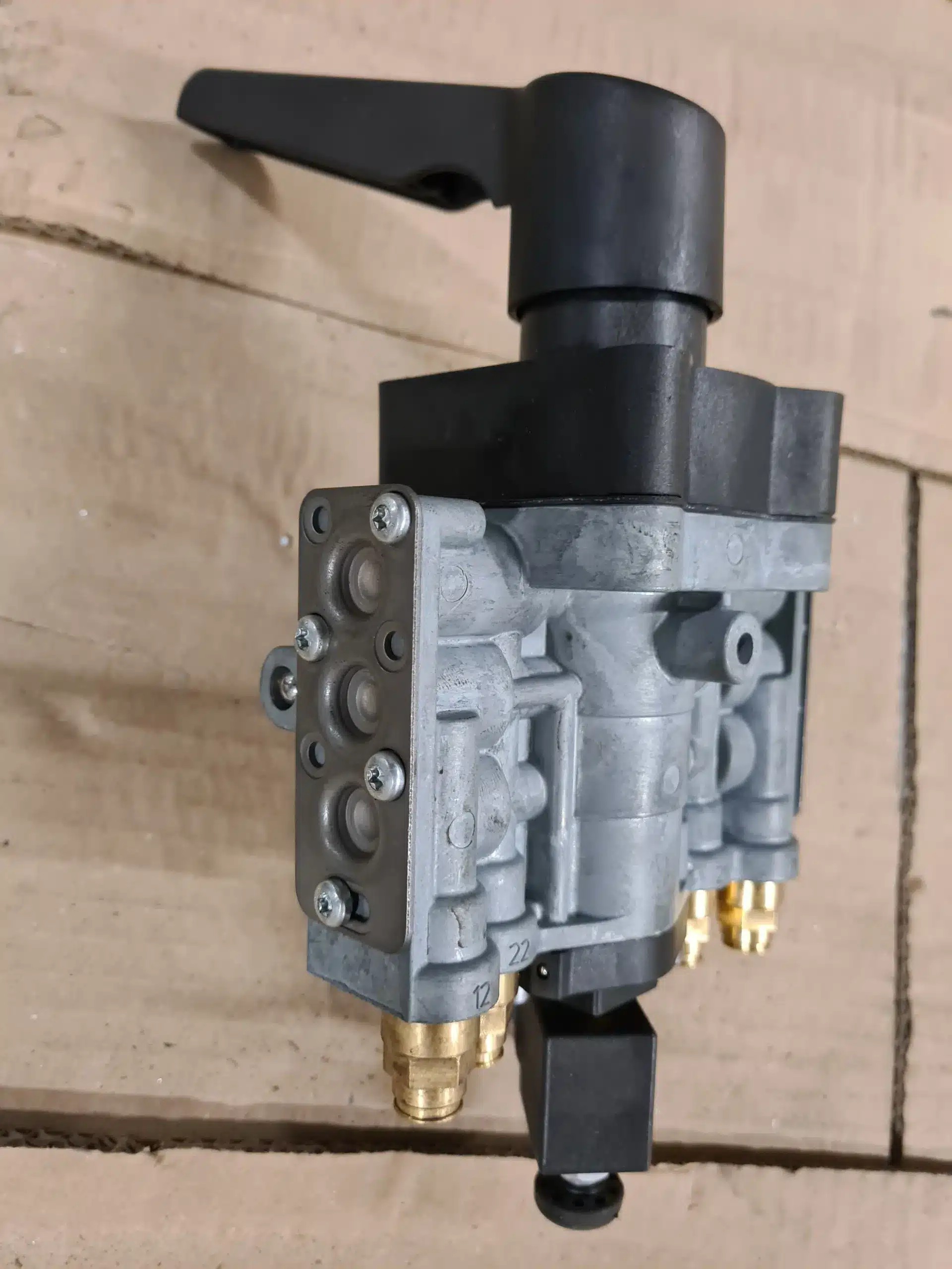 Bloc de valve de commande pneumatique en métal gris avec levier noir. Multiples raccords rapides en laiton, ports étiquetés 12 et 22.